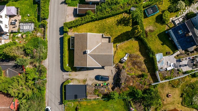 Tomta er opparbeidet med gruslagt gårdsplass på fremsiden av boligen, og stor hage som strekker seg rundt boligen.