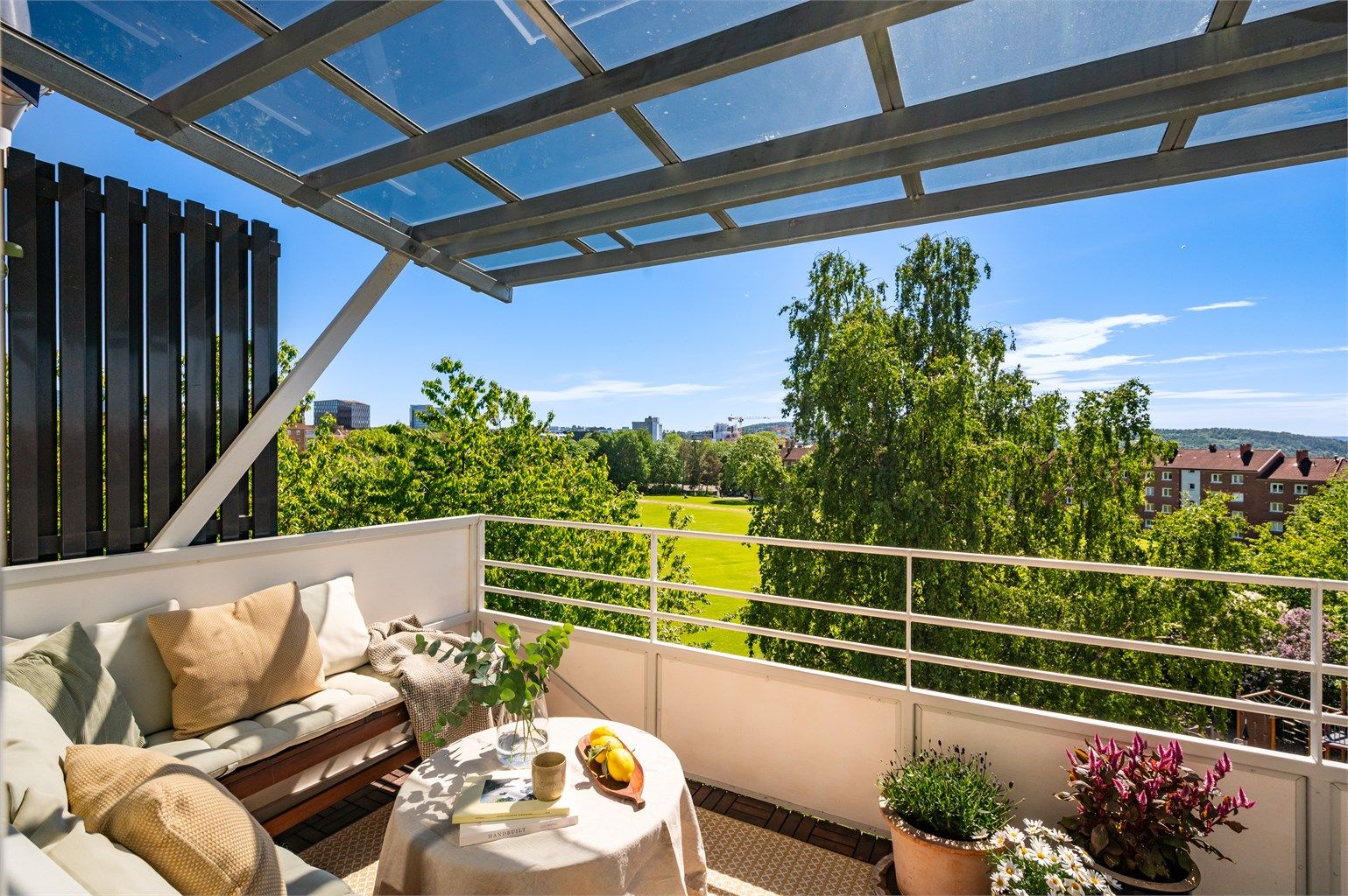 Den overbygde balkongen har god plass til en sittegruppe og vender mot rolige, grønne omgivelser.