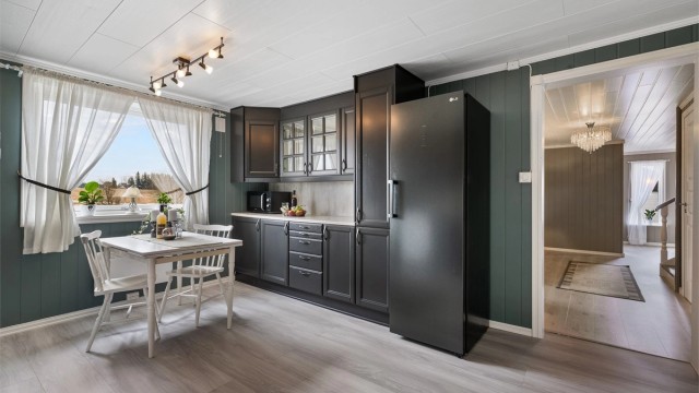 Praktiske doble stikkontakter under overskap. Kjøkkenet er utstyrt med frittstående komfyr plassert i nisje, innebygget oppvaskmaskin og frittstående kjøleskap.