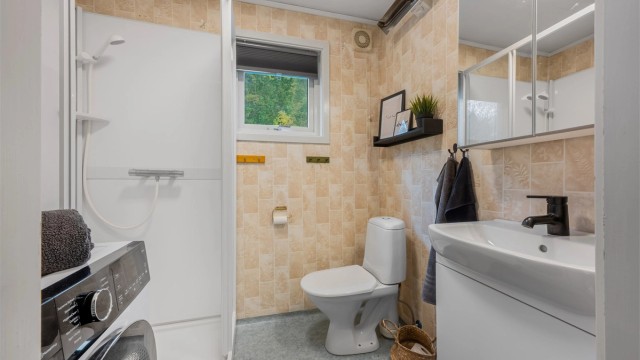 Badet i 1. etasje er innredet med dusjkabinett, toalett, servantmøbel og opplegg for vaskemaskin.