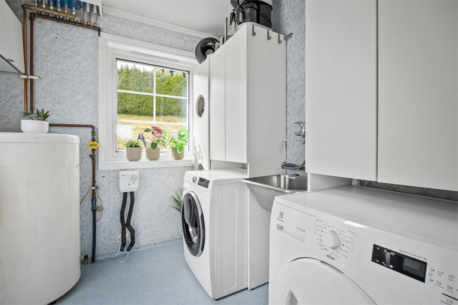 Praktisk vaskerom i første etasje med utslagsvask i stål og opplegg for vaskemaskin.
