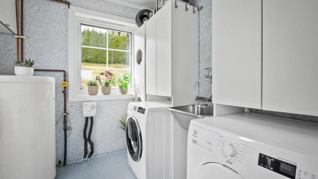 Praktisk vaskerom i første etasje med utslagsvask i stål og opplegg for vaskemaskin.