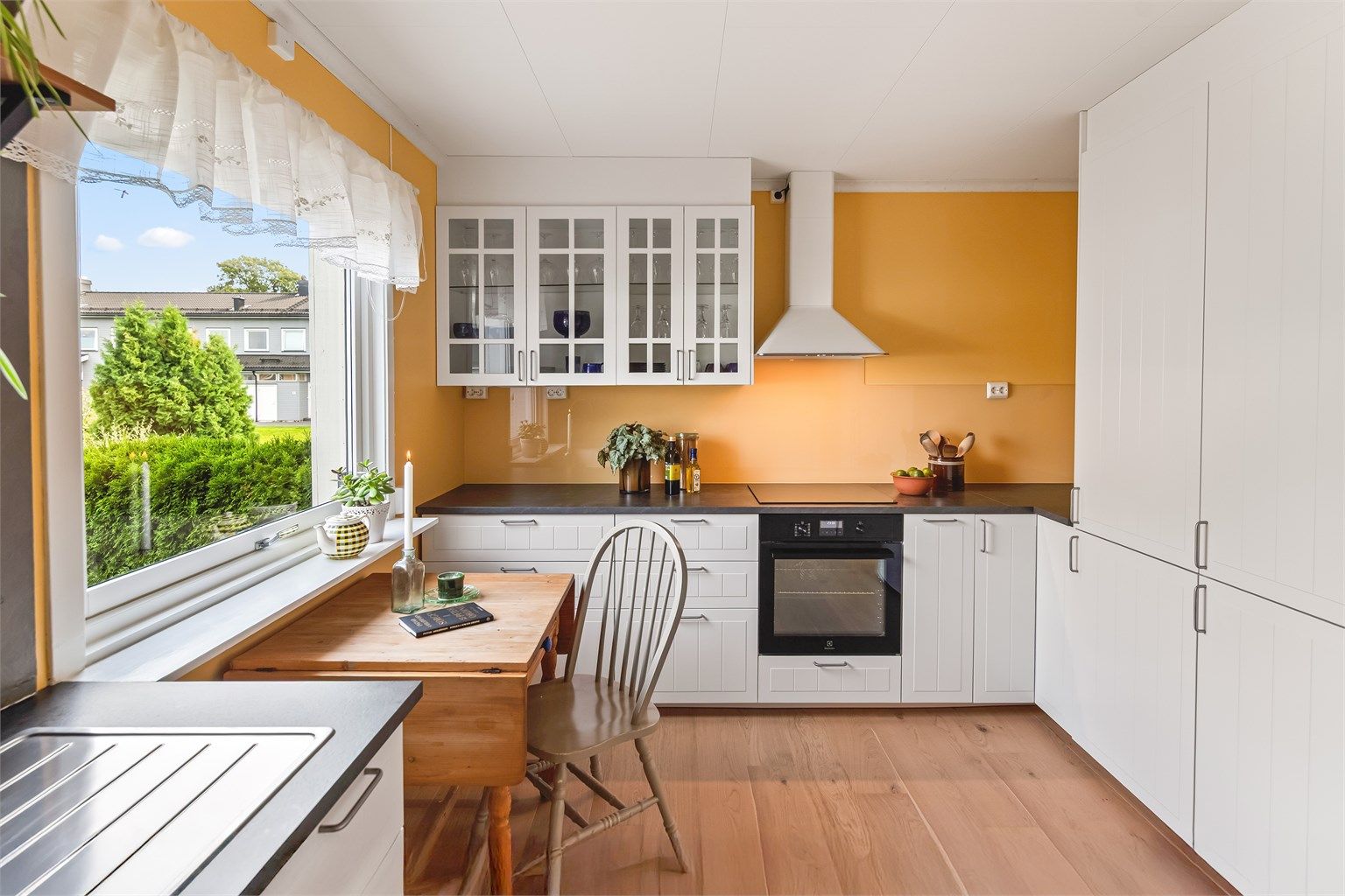 Innredningen har profilerte fronter og laminert benkeplate. Glassplate er montert mellom kjøkkenbenk og overskap. Veggoverflater er malt og på gulv er det lagt eksklusiv 1-stavs parkett. Kjøkkenet er godt utnyttet og har rikelig med skap- og benkeplass. 