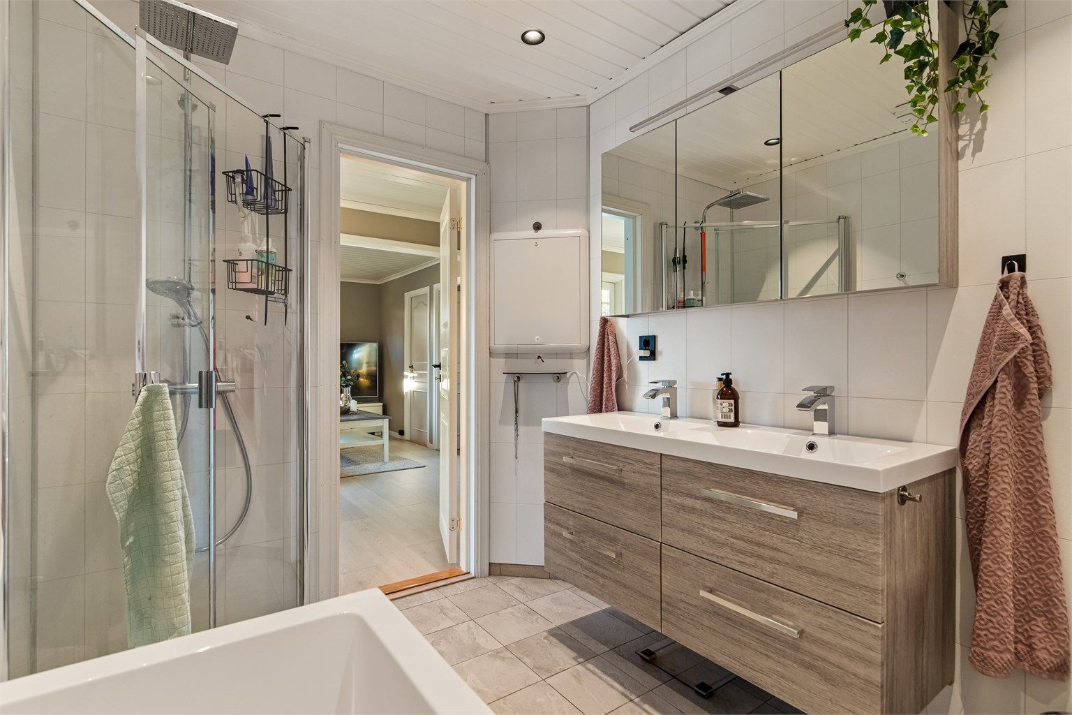 Badet er innredet med dusjhjørne med innfellbare glassdører, regnfall og vegghengt toalett.