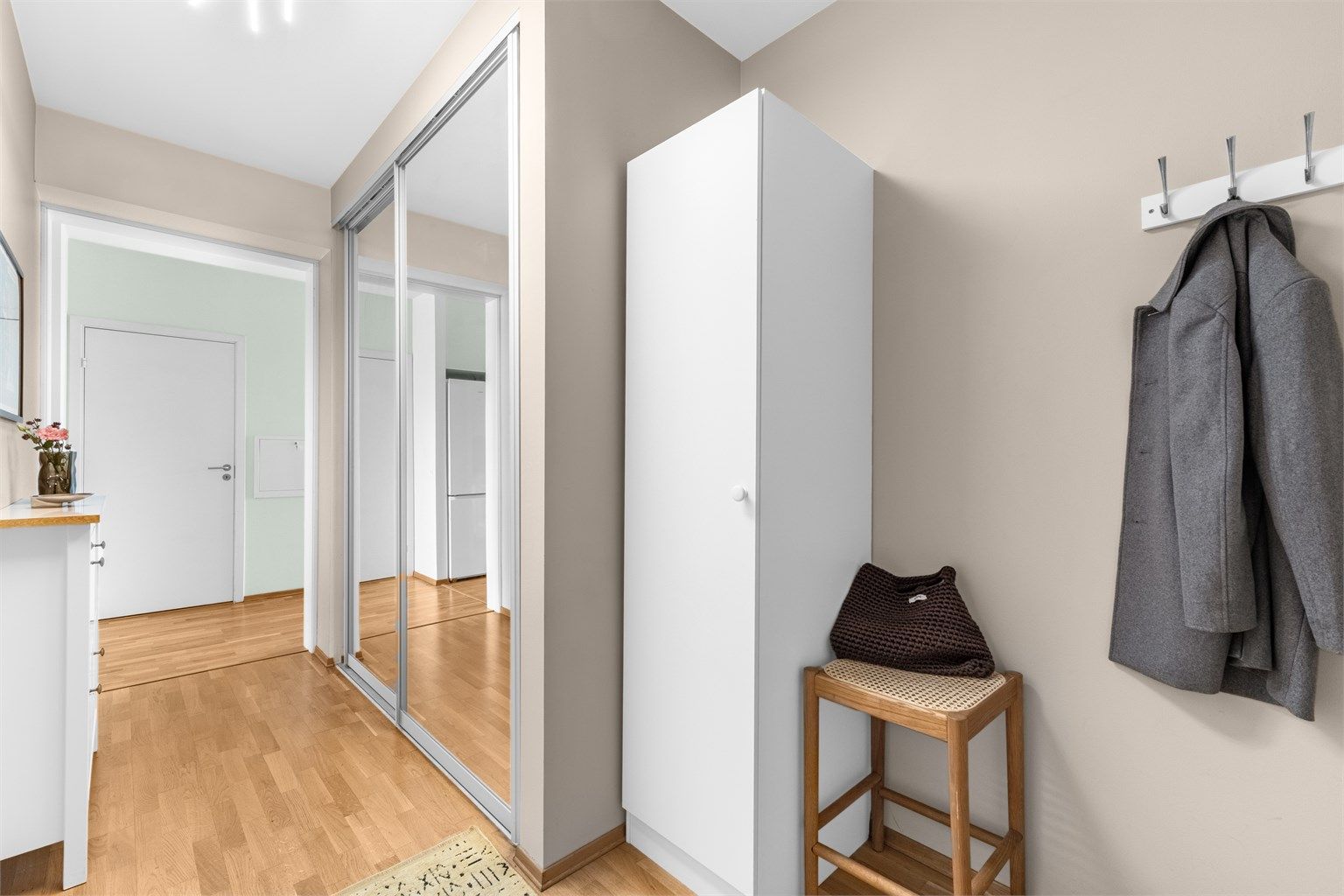 Hyggelig og lys entré med plass til oppbevaring av yttertøy og sko i stor skyvedørsgarderobe med speilfronter.