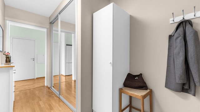 Hyggelig og lys entré med plass til oppbevaring av yttertøy og sko i stor skyvedørsgarderobe med speilfronter.