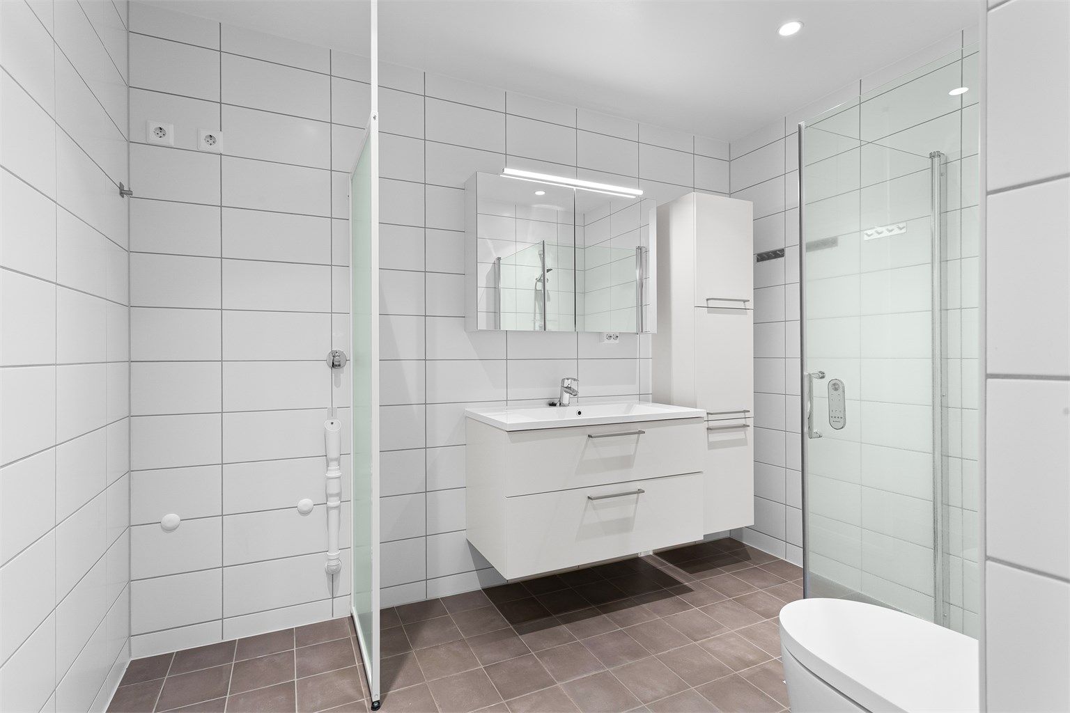 Badet har dusjhjørne med innfellbare glassdører, dusjtoalett og opplegg for vaskemaskin.