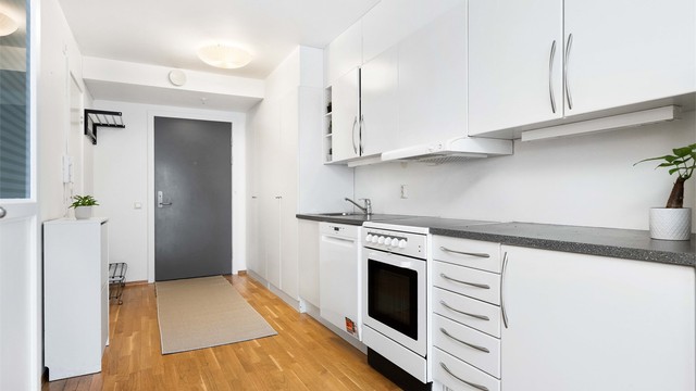 Kjøkkenet har innredning fra byggeår med glatte fronter og laminert benkeplate.