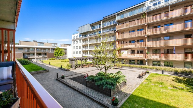 Balkongen har utsikt mot fine fellesarealer og ettermiddagssol (midtsommerstid).
