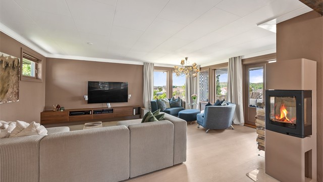 Stuen har direkte utgang til hagen og en peisovn med glassdør som gir god varme.