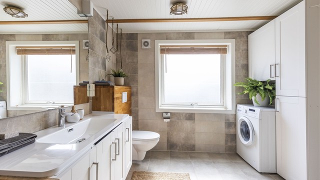 Badet har vegg hengt servant, godt med skapplass, og opplegg for vaskemaskin.