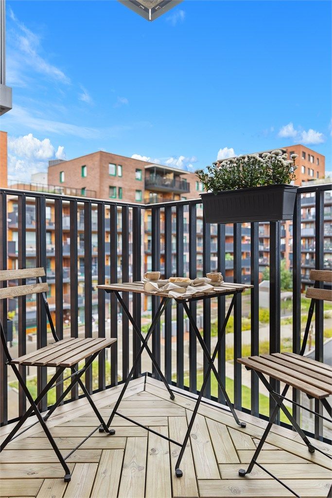 Balkonggulv er belagt med terrassebord, og rekkverket er i metall.