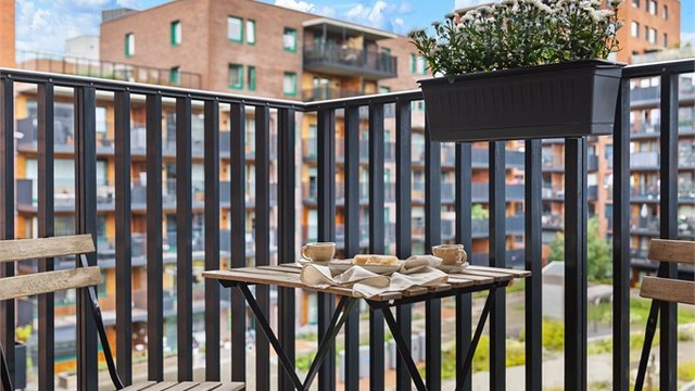 Balkonggulv er belagt med terrassebord, og rekkverket er i metall.