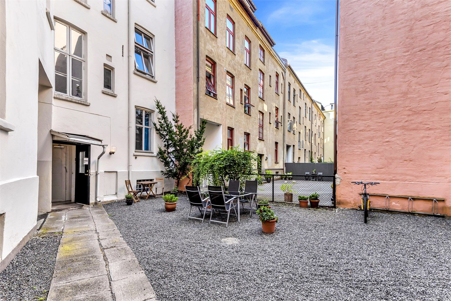 Hyggelig bakgård som er opparbeidet med blant annet gruslagt bakgård med sykkelparkering, samt utearealer med bord og stoler til bruk for beboerne.