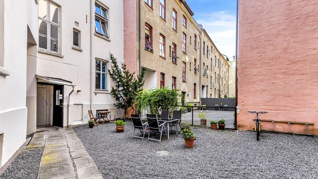 Hyggelig bakgård som er opparbeidet med blant annet gruslagt bakgård med sykkelparkering, samt utearealer med bord og stoler til bruk for beboerne.