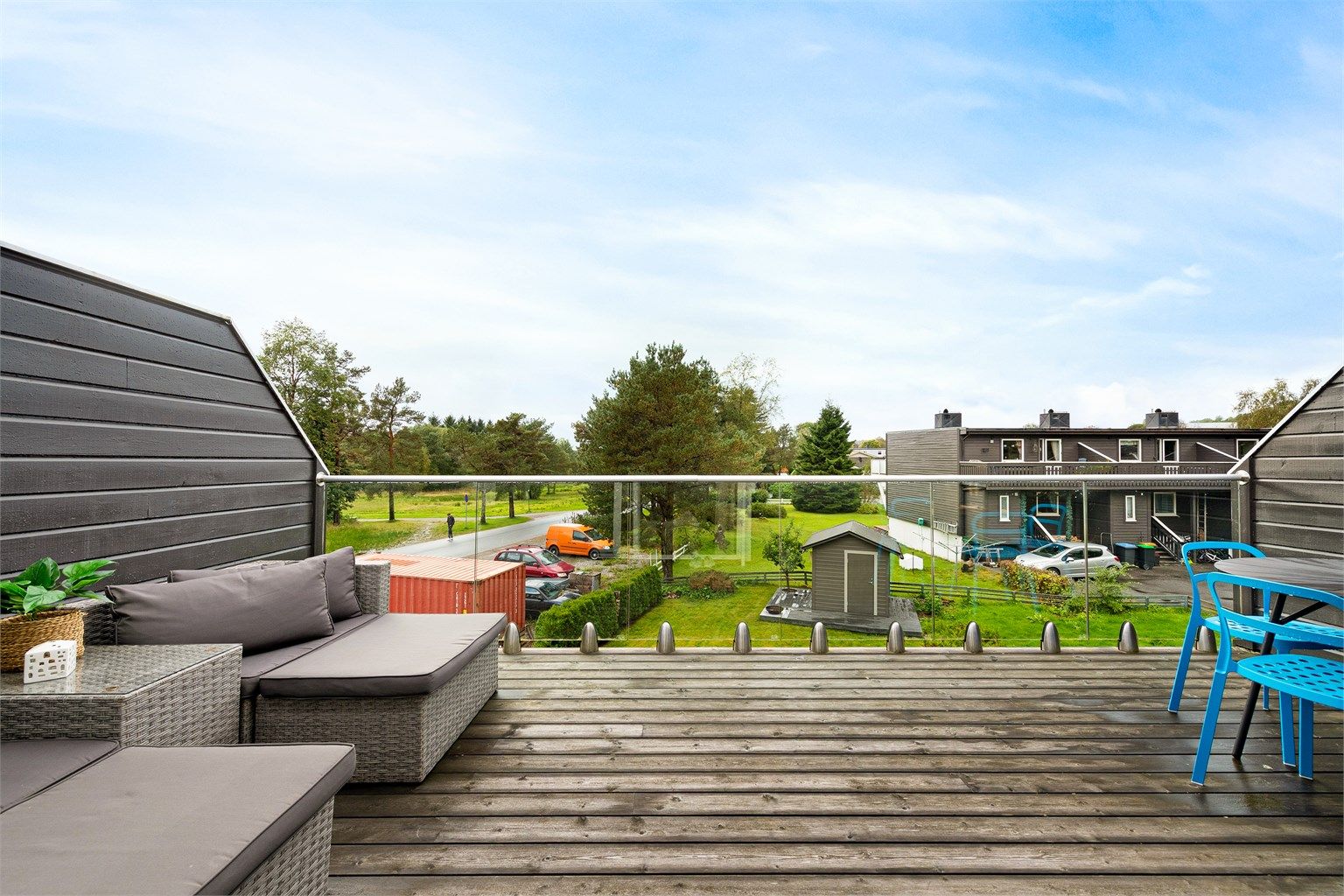 Vestvendt terrasse på 17 kvm med glassrekkverk i front og levegger mot naboer