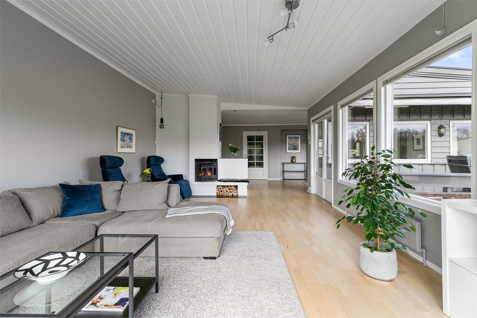 Stor og lys stue med flere soner, peis i hjertet av rommet og utgang til terrasse