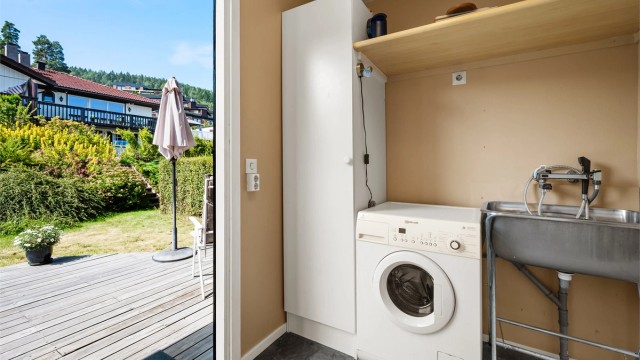 Praktisk vaskerom i boligens 2. etasje med opplegg for vaskemaskin, gulvstående utslagsvask og skap for oppbevaring.