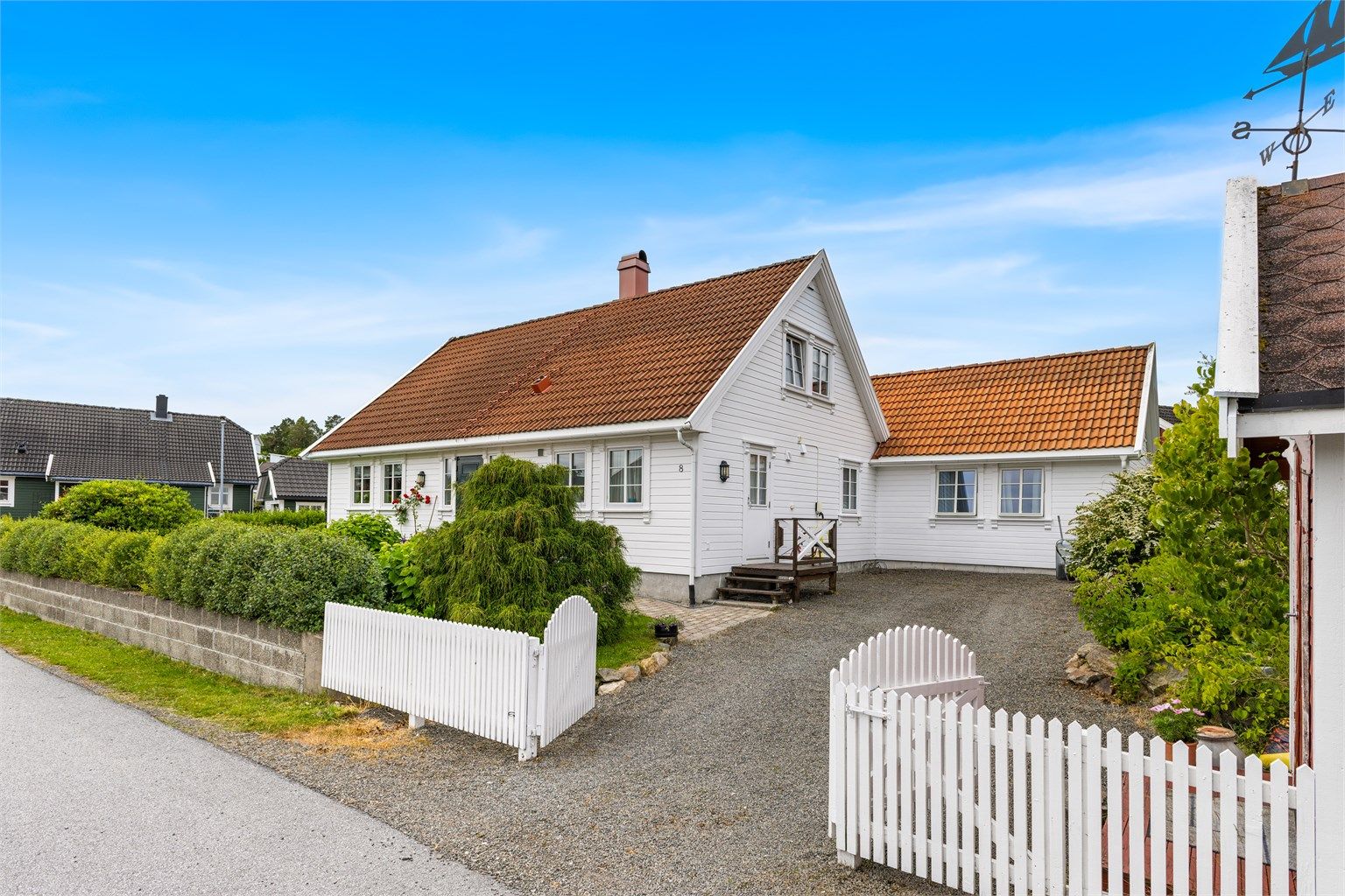 Klassisk fasade med hvitmalt kledning, sprossevinduer og et innbydende inngangsparti.