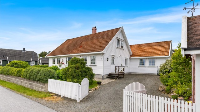 Klassisk fasade med hvitmalt kledning, sprossevinduer og et innbydende inngangsparti.