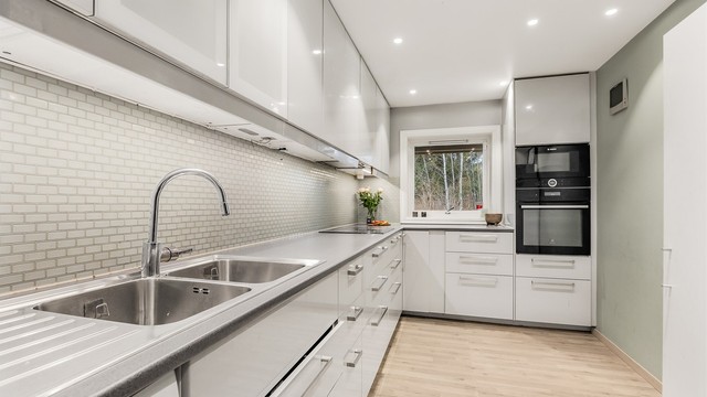 Kjøkkeninnredning fra 2017 med glatte fronter, laminatbenkeplate og fliser over benken.