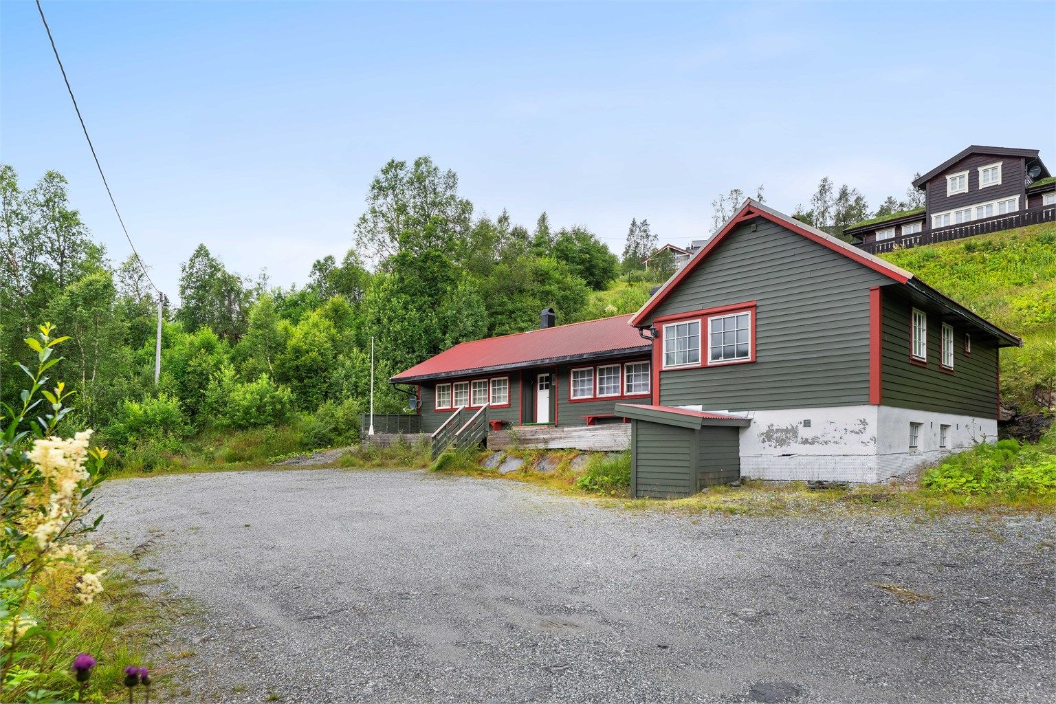 Eiendommen har en stor, gruset gårdsplass med enkel adkomst fra veien.