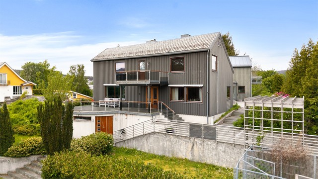 Søndre fasade med store terrasseflater og trappeløp i skifer ned mot hagen.