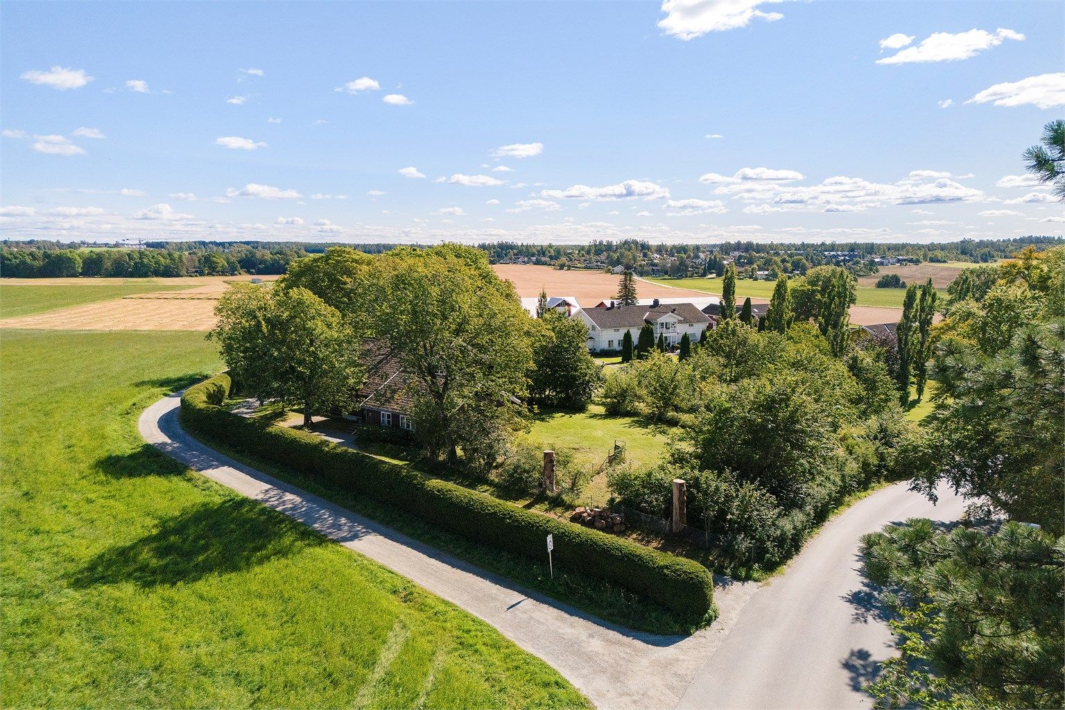 Eiendommen sett fra nord-vest. Granhekken gir god skjerming for vær og vind.