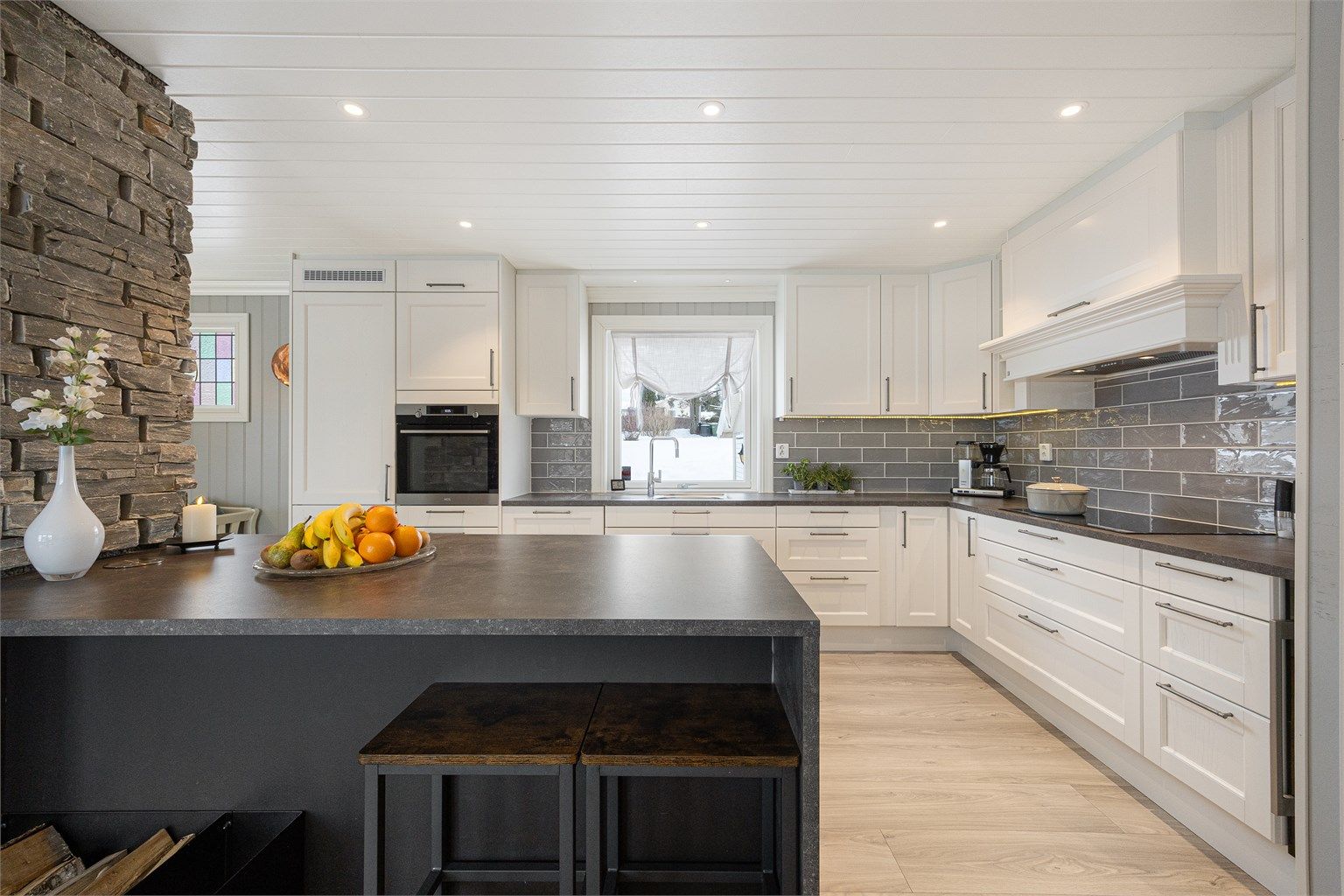 Kjøkkenet fra 2018 har en funksjonell kjøkkenøy med benkeskap og spiseplass.