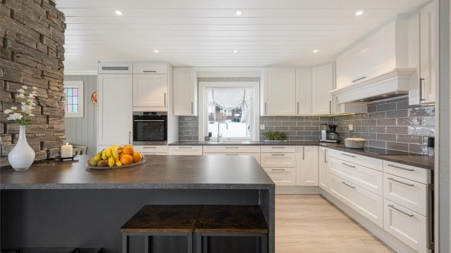 Kjøkkenet fra 2018 har en funksjonell kjøkkenøy med benkeskap og spiseplass.