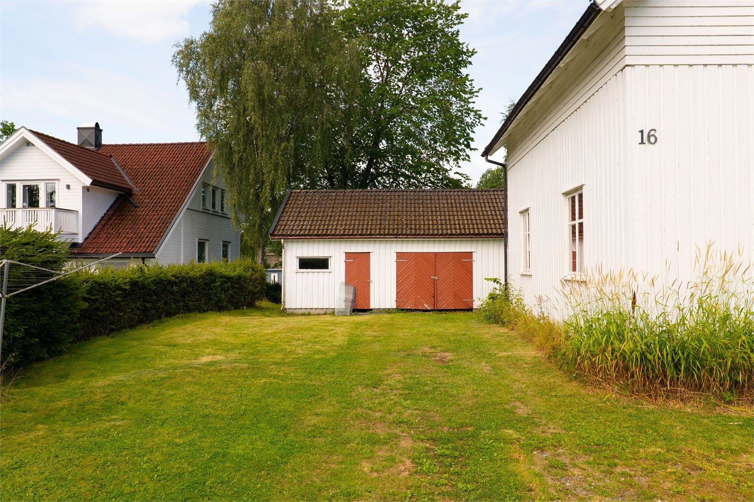 Romslig og grønt uteareal mellom boligen og den frittliggende garasjen.