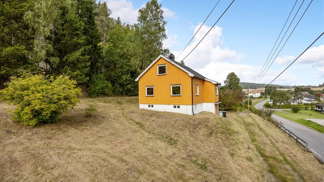 Eiendommen ligger i et åpent landskap med utsikt mot omkringliggende jorder og skog