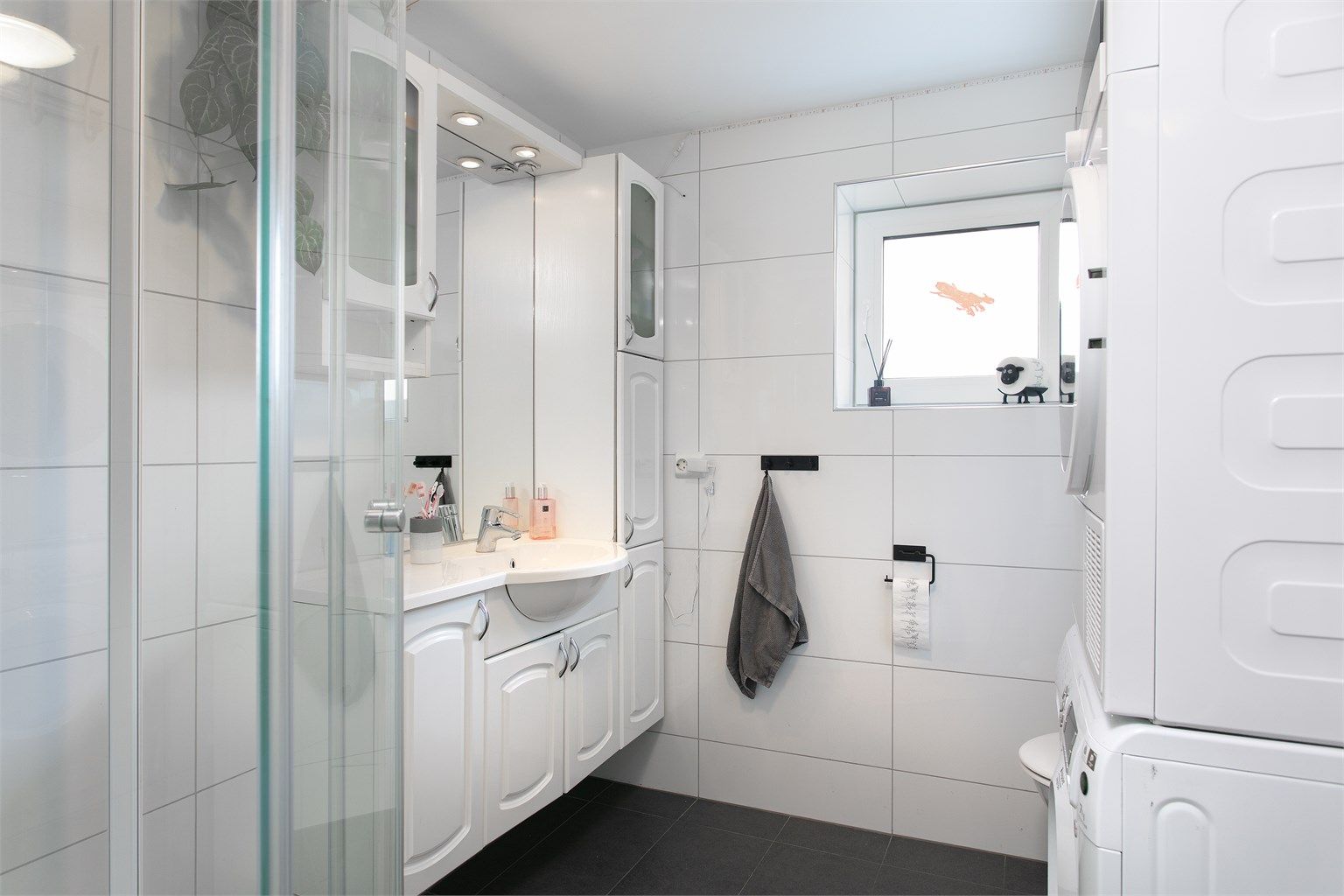 Romslig innredning med nedfelt servant, toalett, dusjakabinett og opplegg for vaskemaskin. Elektrisk styrt vifte.