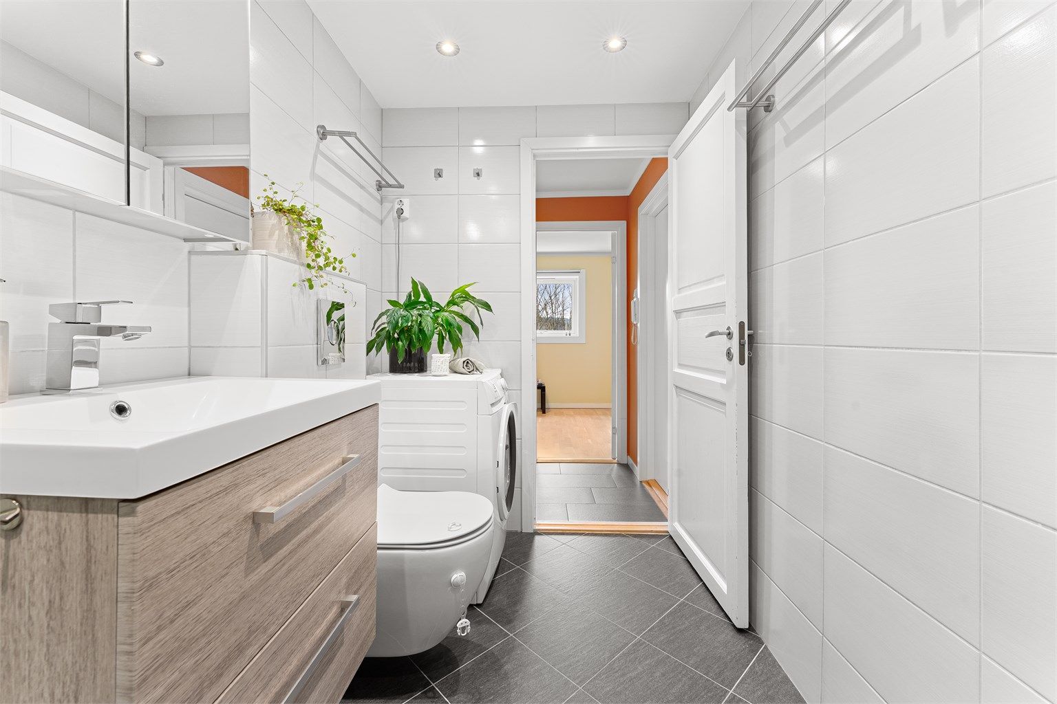 Badet er utstyrt med vegghengt toalett, dusjhjørne med regnfallsdusj og opplegg for vaskemaskin.