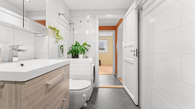 Badet er utstyrt med vegghengt toalett, dusjhjørne med regnfallsdusj og opplegg for vaskemaskin.