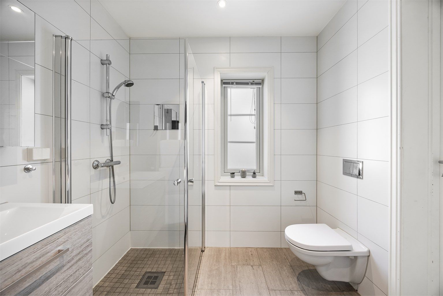 Badet er utstyrt med vegghengt toalett og servantinnredning.