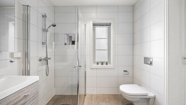 Badet er utstyrt med vegghengt toalett og servantinnredning.