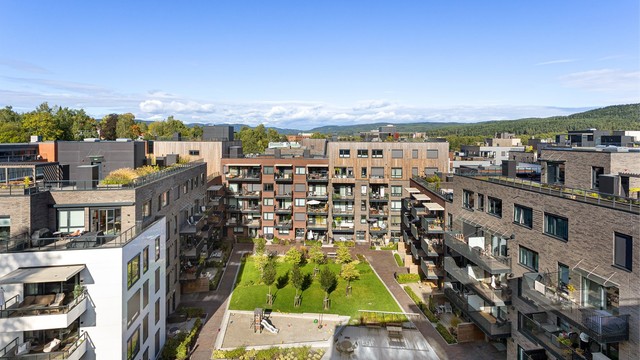 Gårdsrommet har lekeplass, sittebenker og frodige plenarealer.