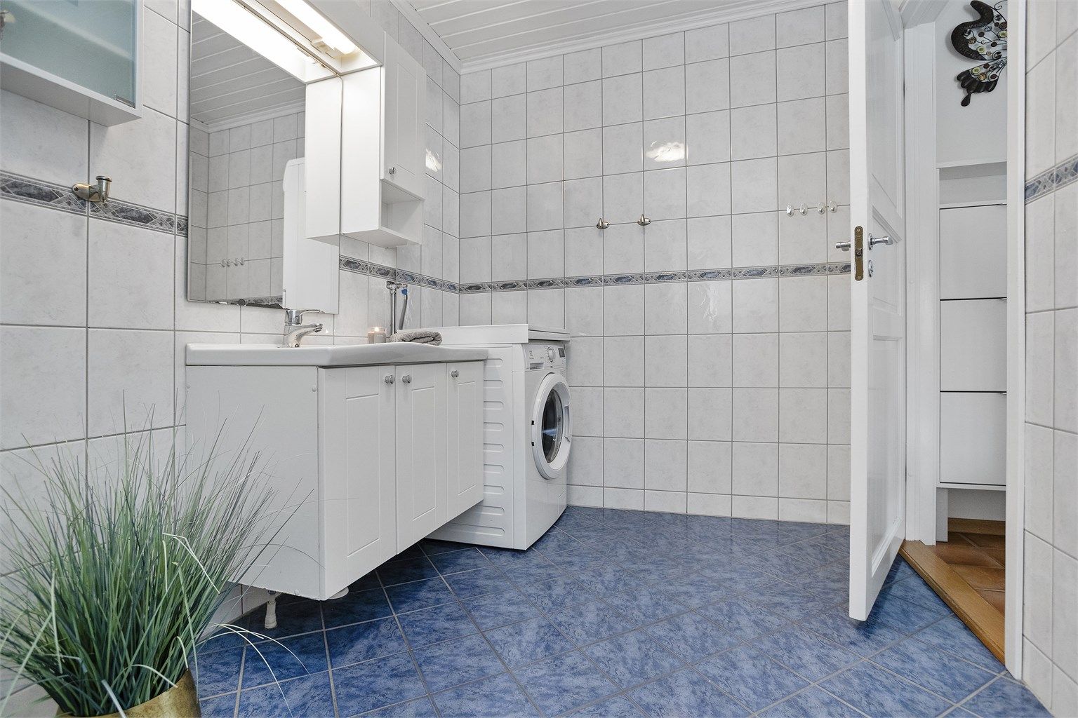 Badet i 1. etasje har flislagt gulv med gulvvarme, servantskap, gulvmontert toalett og dusjkabinett. 