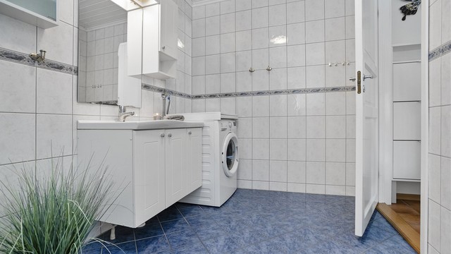Badet i 1. etasje har flislagt gulv med gulvvarme, servantskap, gulvmontert toalett og dusjkabinett.