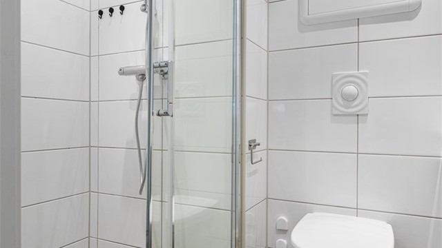 Badet er kompakt, men er utstyrt med alt det nødvendige. Praktisk dusjnisje med skyvedør og dusjgarnityr, samt vegghengt toalett
