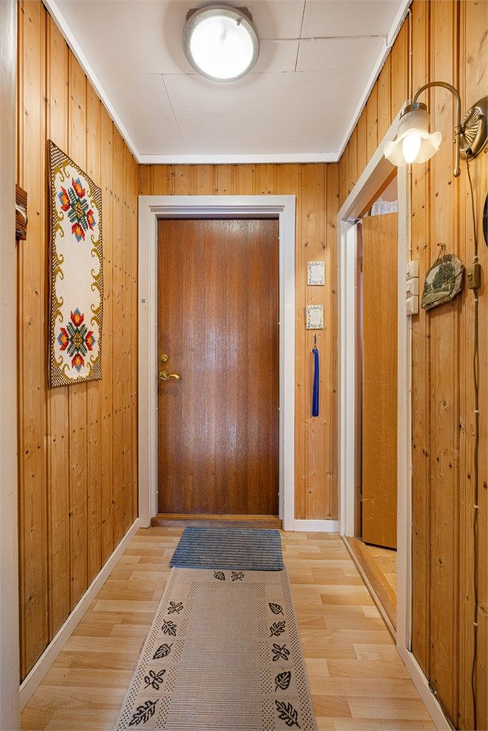 Inngangspartiet ønsker velkommen med panelkledde vegger og laminat på gulvet.