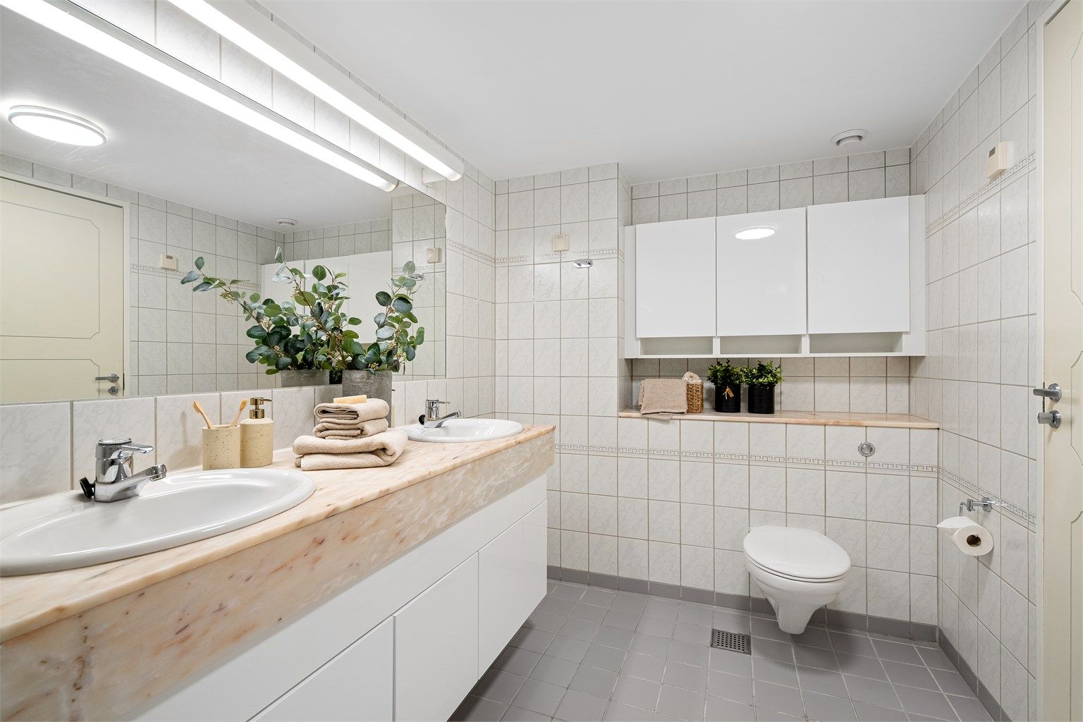 Det er varmekabler i gulv, servant med marmor, stort speil på vegg. Ekstra oppbevaring i skap på vegg. 