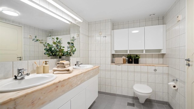 Det er varmekabler i gulv, servant med marmor, stort speil på vegg. Ekstra oppbevaring i skap på vegg.