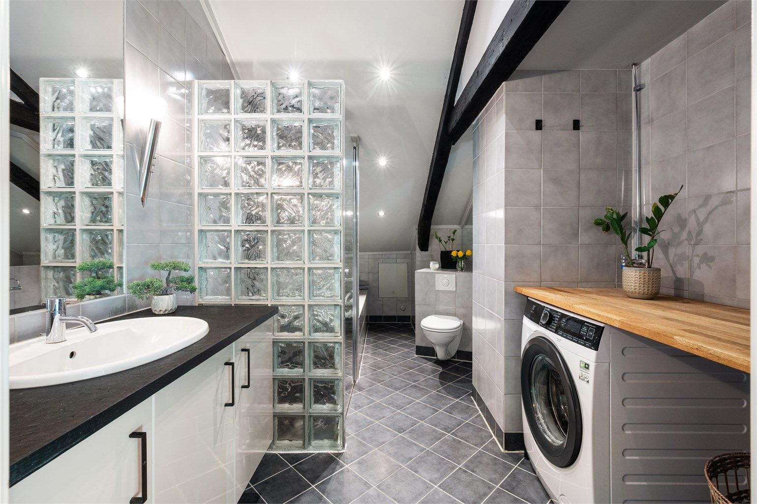 Baderom bestående av baderom, dusjnisje med glassvegg og glassdør, badekar, vegghengt toalett og vegghengt servantinnredning.