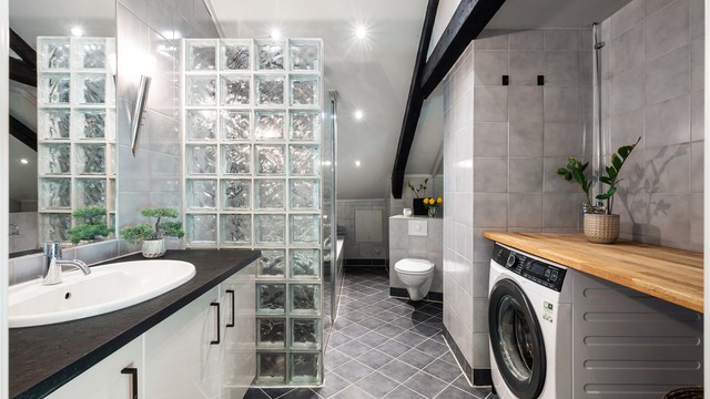 Baderom bestående av baderom, dusjnisje med glassvegg og glassdør, badekar, vegghengt toalett og vegghengt servantinnredning.