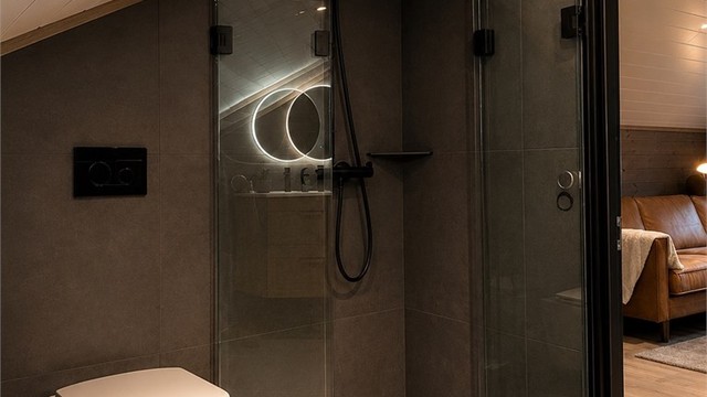 Badet har store, moderne fliser og sorte detaljer
