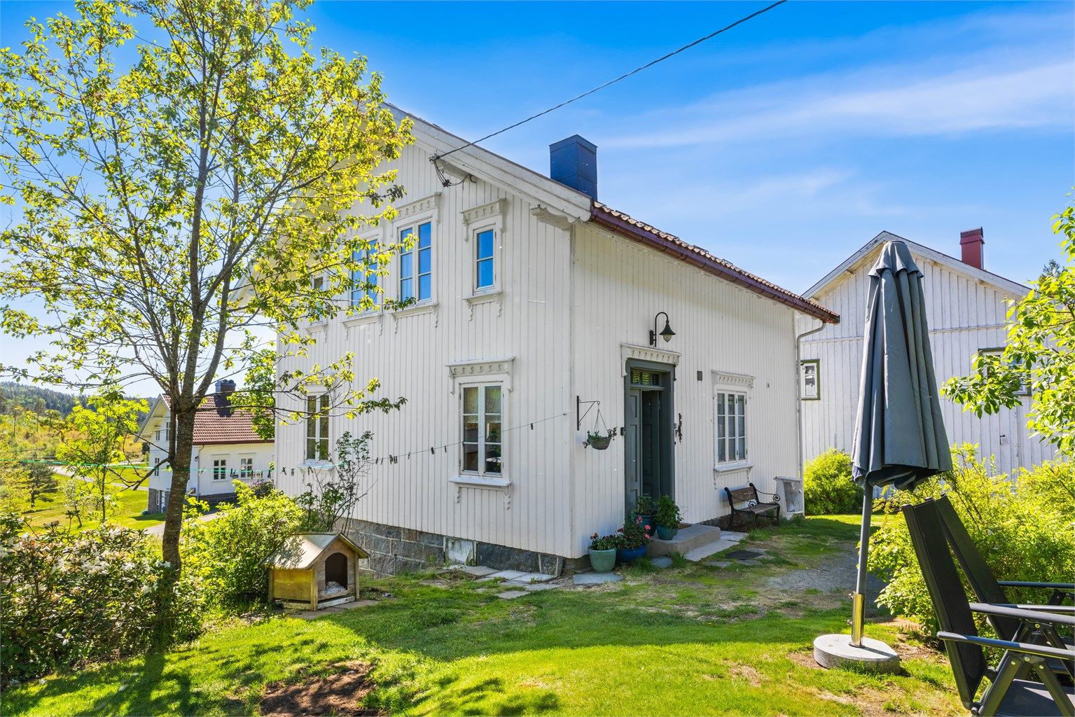 Våningshuset har en klassisk stil med stående trekledning og grunnmur i naturstein.