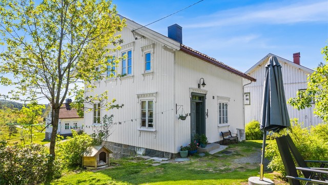 Våningshuset har en klassisk stil med stående trekledning og grunnmur i naturstein.
