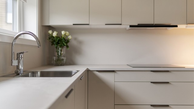 De sorte håndtakene mot den beige innredningen gir et tidløst og moderne uttrykk. Kjøkkenvinduet gir både behagelig utsyn og lysinnslipp, i tillegg til benkeskapsbelysning og spotter i tak